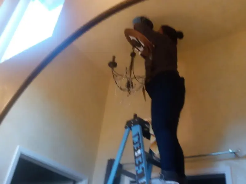 Electrician installing a chandelier in a Marathon residence